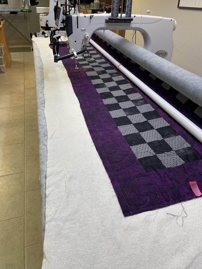 Purple and black checkerboard quilt on the longarm machine