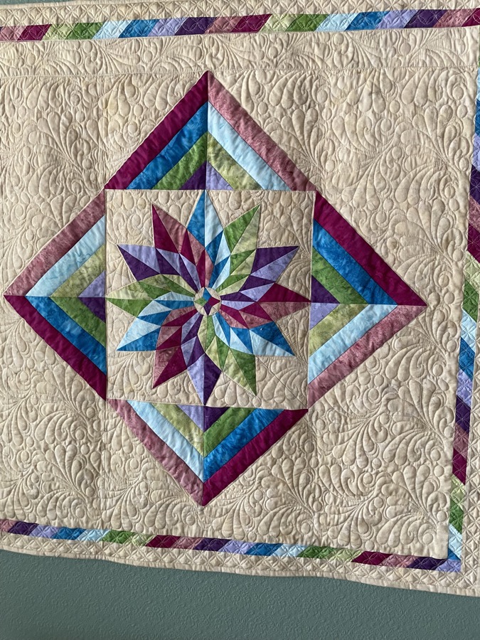 Star medallion quilt with feather quilting, purple blue and green