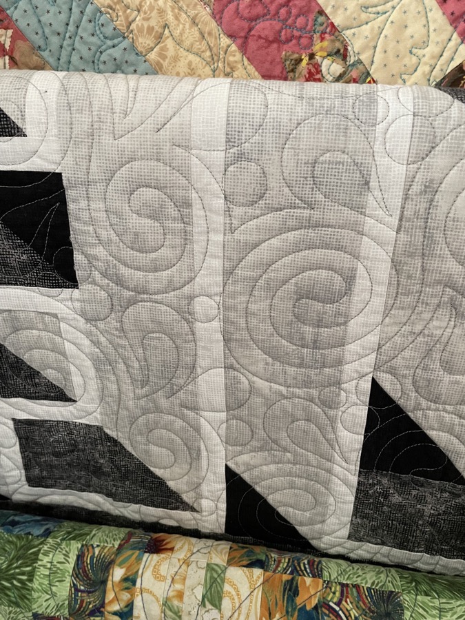 Close up of spiral swirl computerized quilting pattern on white fabric